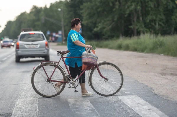 Старшая женщина, переходящая дорогу на велосипеде, Россия — стоковое фото