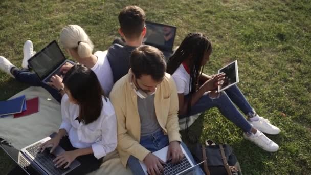 Diverse vrienden met behulp van gadgets tijdens het studeren buiten — Stockvideo