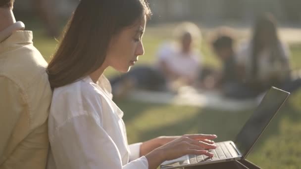 Enkele studenten die buiten op laptops werken — Stockvideo