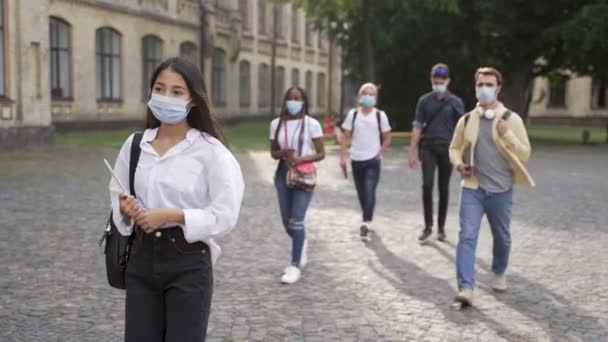 Wielorasowi studenci w maskach do chodzenia na zajęcia — Wideo stockowe