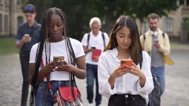 นักเรียนหลายเชื้อชาติใช้โทรศัพท์มือถือระหว่างการเดิน — วีดีโอสต็อก