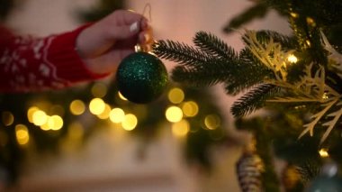Köknar ağacına Noel topu asan bir kızın eli