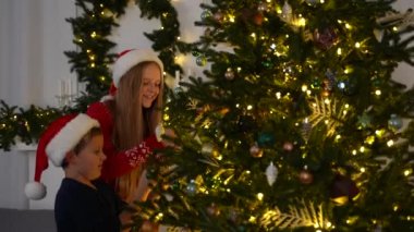 Mutlu çocuklar Noel ağacına oyuncak asıyor.