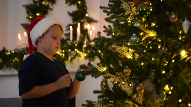Evdeki Noel ağacını süsleyen sevimli küçük çocuk. — Stok video