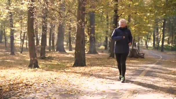 Fit senior woman during cardio training in nature — Video