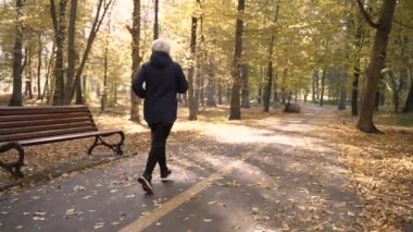 Fit aged woman jogging outdoor on sunny autumn day