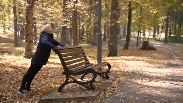 Fit aged woman doing push-ups in autumn park — Video