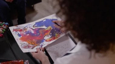 Çocuk hasta ve psikolog resme bakıyor.