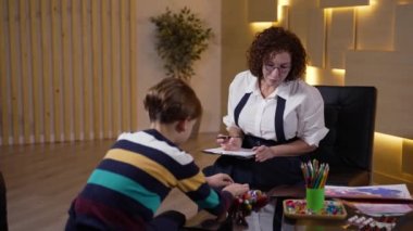 Kadın psikolog muayenede çocuğu test ediyor.