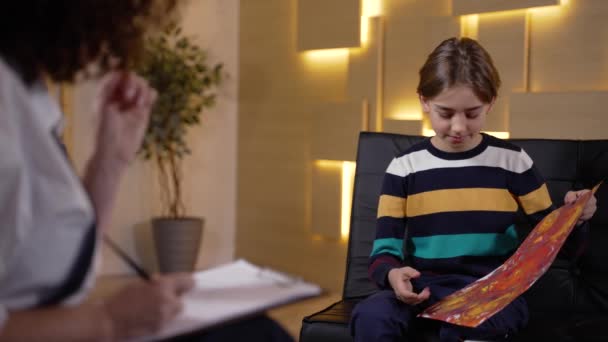 Child talking about his painting to psychologist — Stockvideo