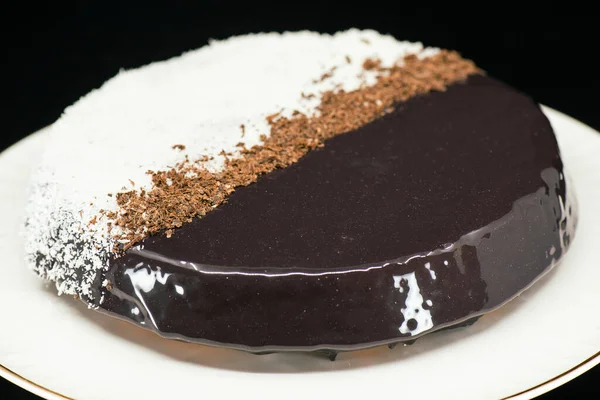 Detailed close up of a lamington mirror glaze single tier cake with shredded coconut and dark chocolate