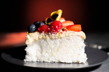 Bir dilim pavlova, içinde çilek, ahududu, yabanmersini, çarkıfelek meyvesi hamuru ve krema bulunan taze meyveli bir Avustralya tatlısı..