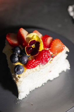 Bir dilim pavlova, içinde çilek, ahududu, yabanmersini, çarkıfelek meyvesi hamuru ve krema bulunan taze meyveli bir Avustralya tatlısı..