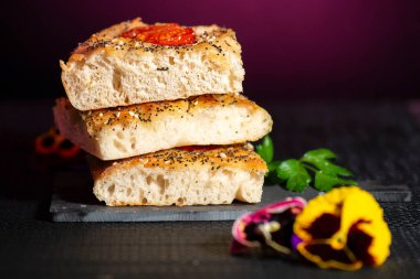 Çeri domates, haşhaş ve susam tohumları, biber, Himalaya kaya tuzu ve karışık bitkilerle taze pişmiş Focaccia.. 