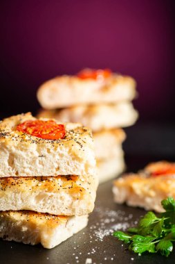 Çeri domates, haşhaş ve susam tohumları, biber, Himalaya kaya tuzu ve karışık bitkilerle taze pişmiş Focaccia.. 