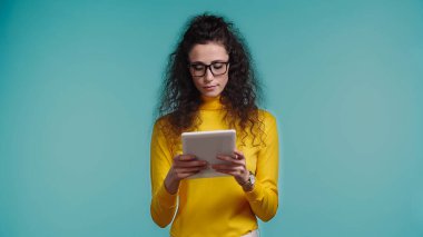 Dijital tablet kullanan mavi gözlüklü genç kıvırcık kadın.