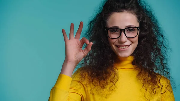 Vrolijke Jonge Vrouw Bril Tonen Teken Geïsoleerd Blauw — Stockfoto