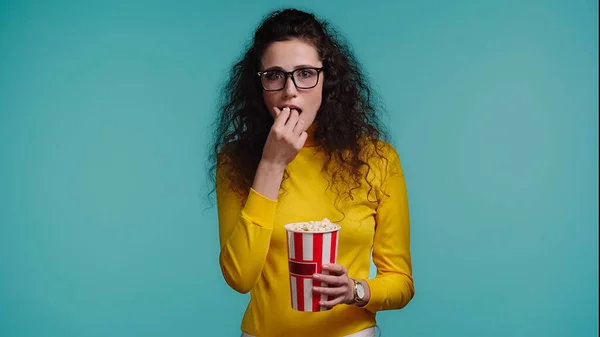 Kudrnatá Mladá Žena Drží Kbelík Při Jídle Popcorn Izolované Modré — Stock fotografie