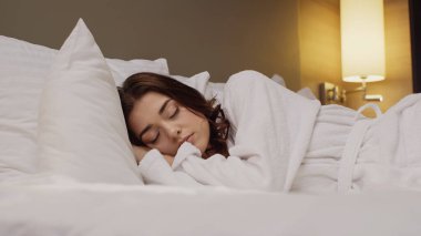 Otel yatağında uyuyan genç bir kadının yüzey manzarası.