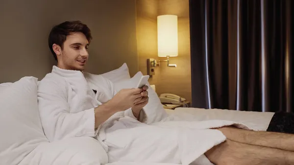 Happy Young Man Bathrobe Using Smartphone While Resting Hotel Room — Stock Photo, Image