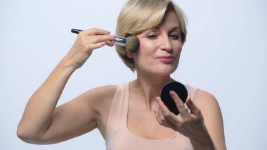 Gülümseyen orta yaşlı kadın mükemmel cilt pudrası uygulayan beyaz tenli.