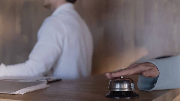 cropped view of client pressing service bell near hotel receptionist