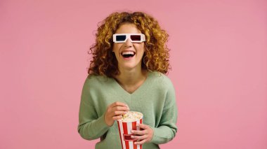 Üç boyutlu gözlüklü heyecanlı kadın pembe bir film izlerken gülüyor.
