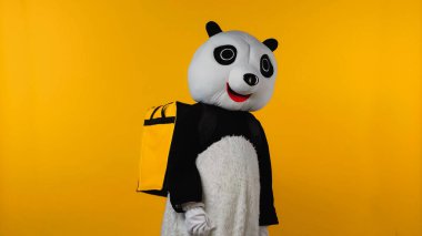 Sırt çantalı, sarı renkli panda kostümlü kişi. 