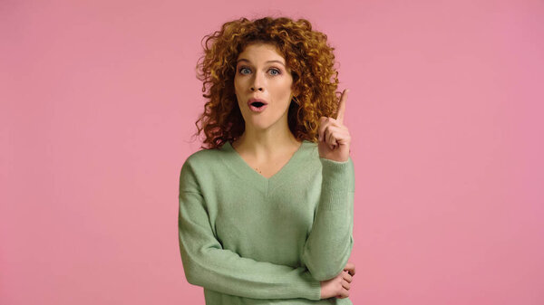 amazed woman with open mouth showing idea gesture isolated on pink