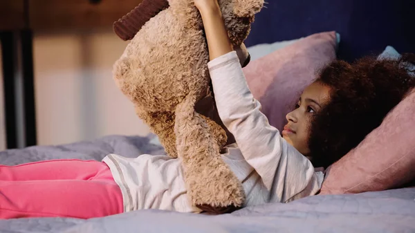 Göndör Afro Amerikai Gyermek Fekszik Tartja Teddy Maci Ágyban — Stock Fotó