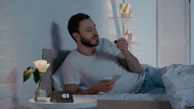 Genç adam gece yatakta çikolataya bakıyor. 