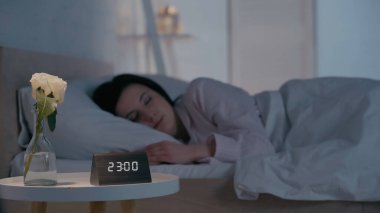 Çiçek ve saat komodinin yanında bulanık esmer kadının evinde uyuyor. 