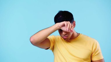 Yorgun adam terini siliyor ve yanaklarını şişiriyor.