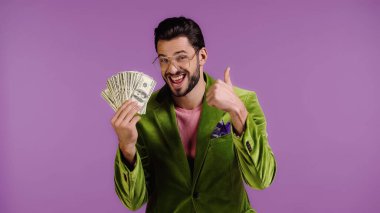 Yeşil ceketli, gözlüklü, elinde dolar olan mutlu bir adam.
