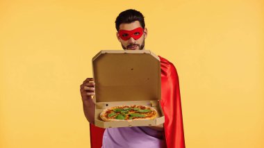 Süper kahraman kostümlü sakallı adam. Sarı kutuda pizza izole edilmiş.