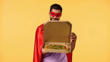 Süper kahraman kostümlü mutlu adam. Sarı renkli pizzalı açılış kutusu.