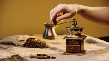 cropped view of man grinding coffee beans near blurred coffee pot  clipart