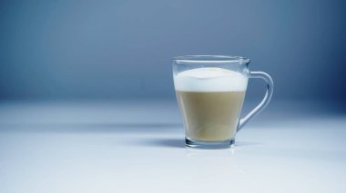 coffee latte with white foam in glass on grey  clipart