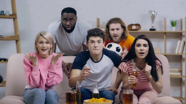 heyecan verici çok ırklı spor hayranları evde TV 'de futbol şampiyonası izlerken el kol hareketi yapıyorlar.