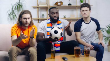 Memlekette TV 'de futbol maçı seyreden çok ırklı taraftarlar ellerini kaldırıyor.