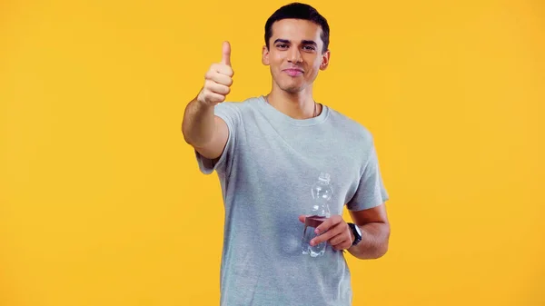 Feliz Joven Camiseta Sosteniendo Botella Con Agua Mostrando Pulgar Hacia —  Fotos de Stock