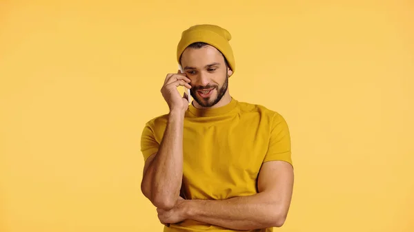 ビーニー ハットの陽気な男が黄色で隔絶されたスマートフォンで話しています — ストック写真