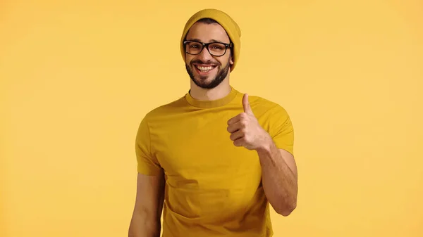 Счастливый Молодой Человек Шапочке Очках Футболке Показывающий Большой Палец Желтом — стоковое фото