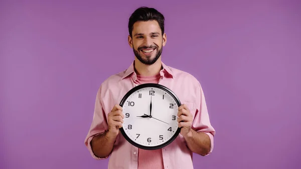 Happy Young Man Pink Shirt Holding Clock Isolated Purple — стоковое фото