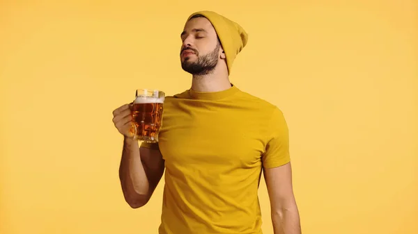 Joven Gorro Sombrero Camiseta Sosteniendo Taza Vidrio Oliendo Cerveza Aislada — Foto de Stock