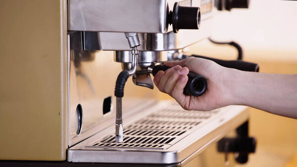 partial view of barista putting coffee filter holder