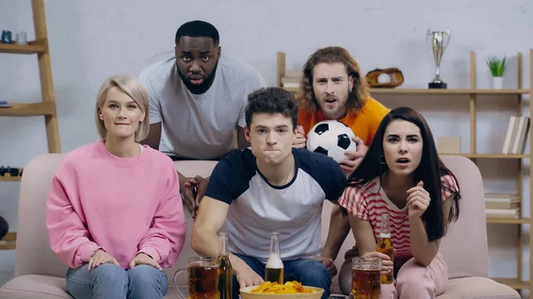 Bira ve cips yakınlarında şampiyonluk maçı izleyen gergin ve konsantre futbol taraftarları