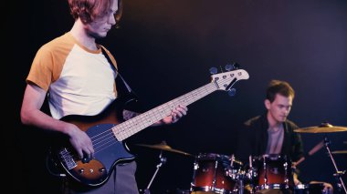 KYIV, UKRAINE - DECEMBER 30, 2021: rock guitarist playing near blurred drummer on stage 