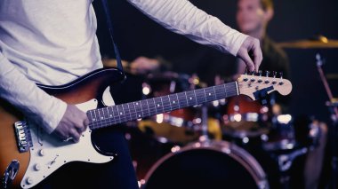 KYIV, UKRAINE - DECEMBER 30, 2021: cropped view of guitarist rehearsing near drummer 