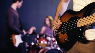 KYIV, UKRAINE - DECEMBER 30, 2021: cropped view of tattooed guitarist playing with blurred band on stage 